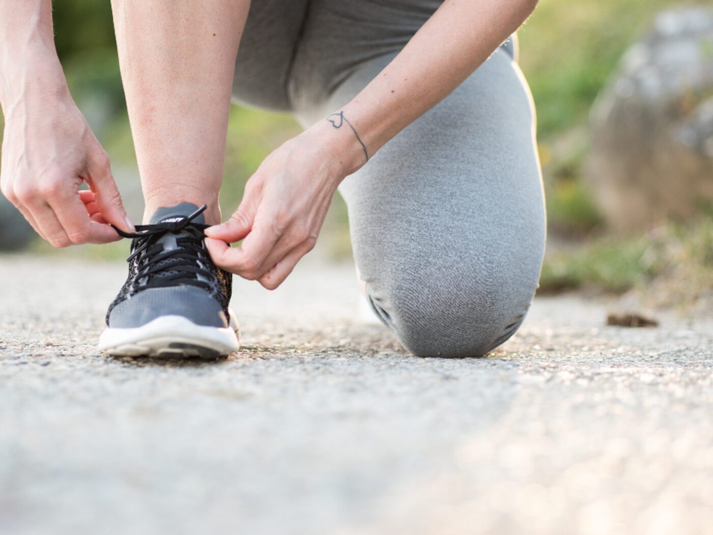 Close-up of someone kneeling to lace a running shoe before setting off.