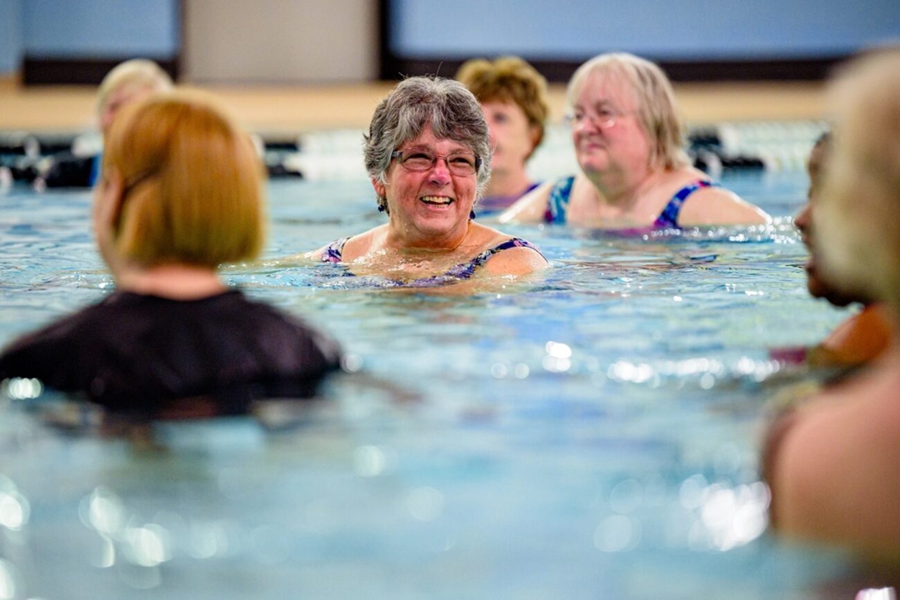 A group of older adults exercising together in a swimming pool.