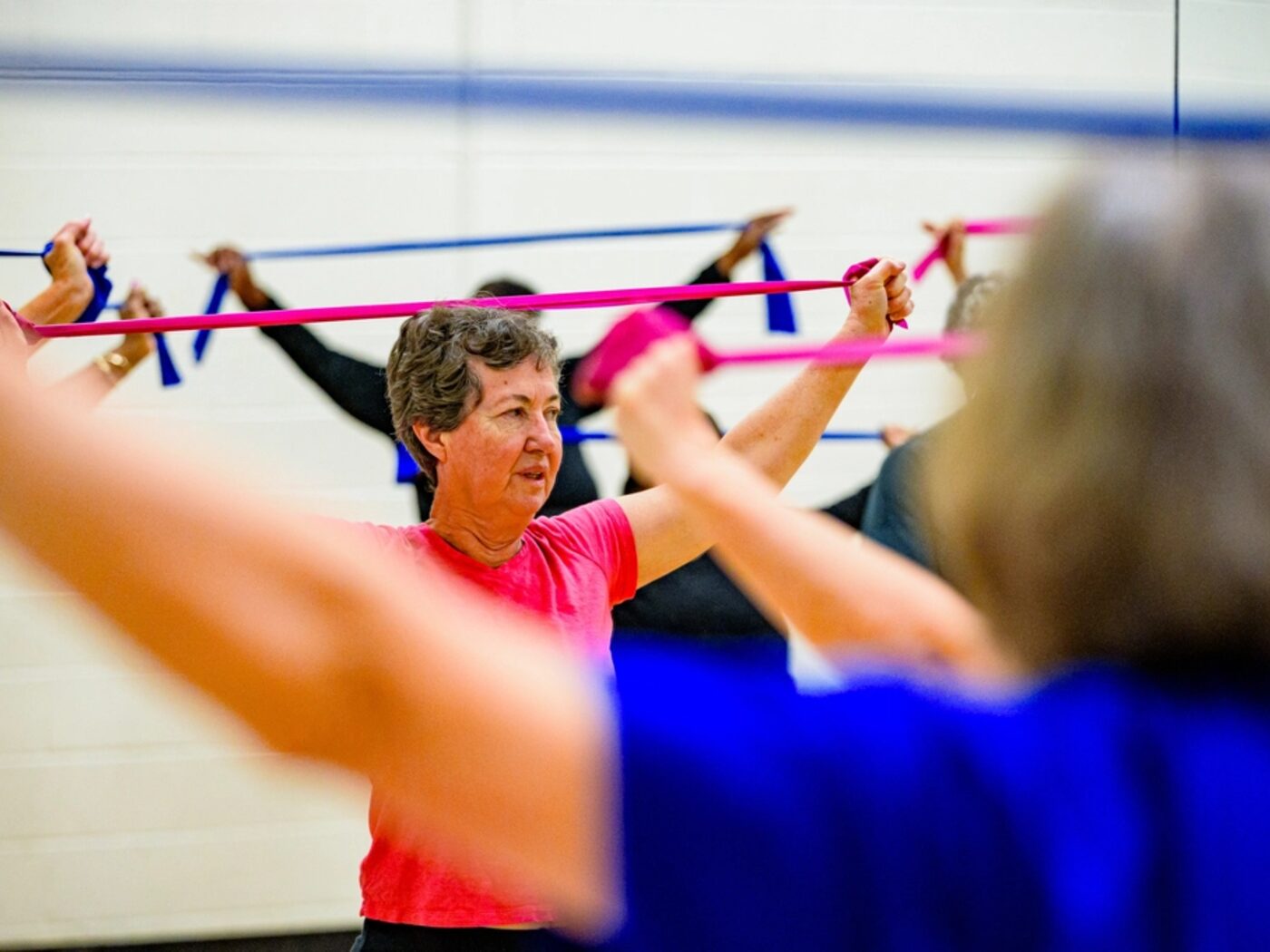 Two older adults working through a resistance-band exercise in a class.